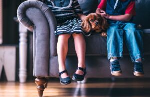 Two children sitting on a sofa with a dachshund between them