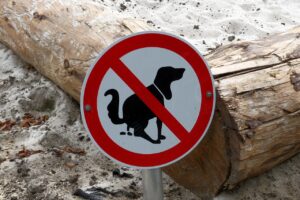 A red and white sign prohibiting dog fouling, fixed beside a log